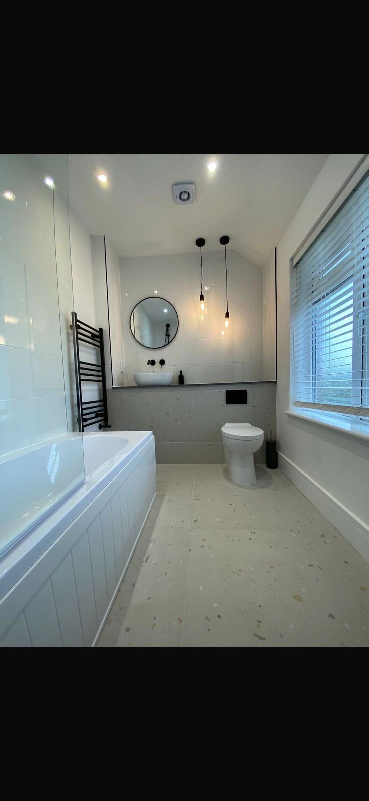 A terrazzo bathroom with a black towel rail