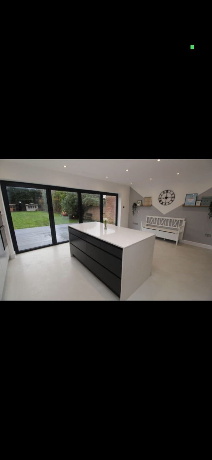 An open-plan kitchen with a black island and bi-fold doors