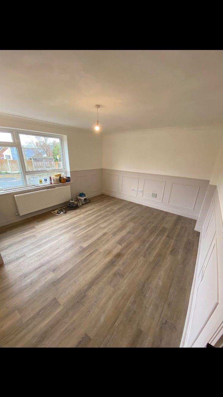 A bedroom with white panelling and wood-effect flooring