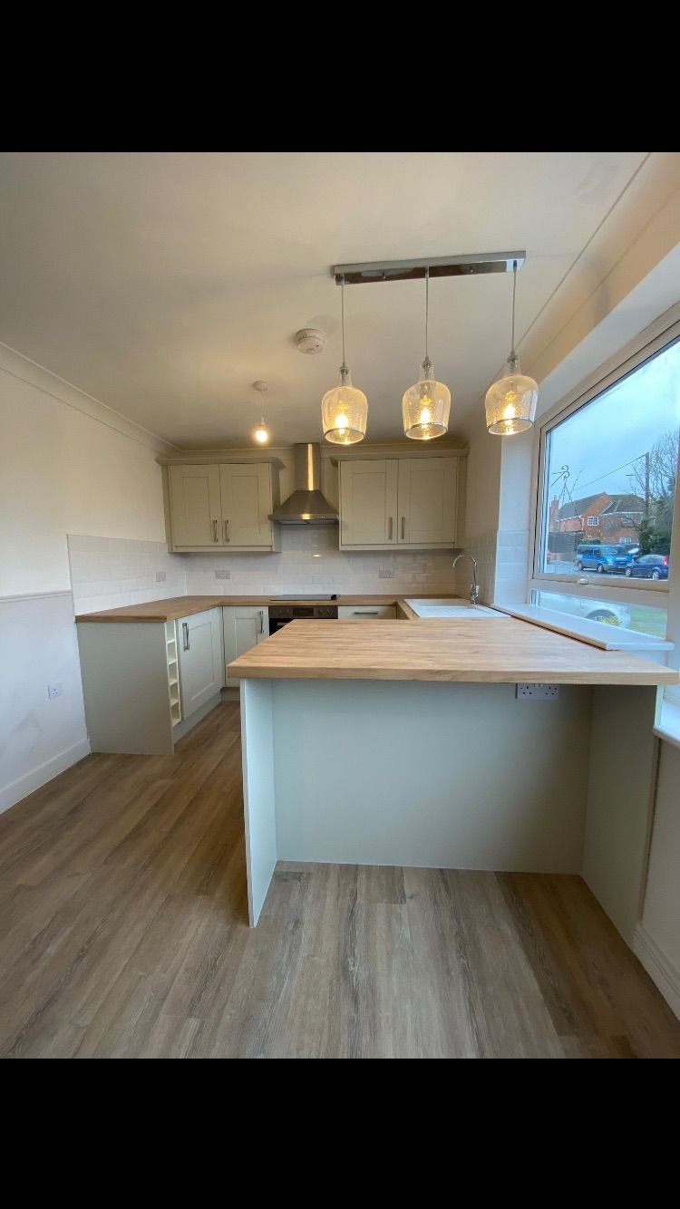 A sage kitchen with laminate worktops and pendant lights