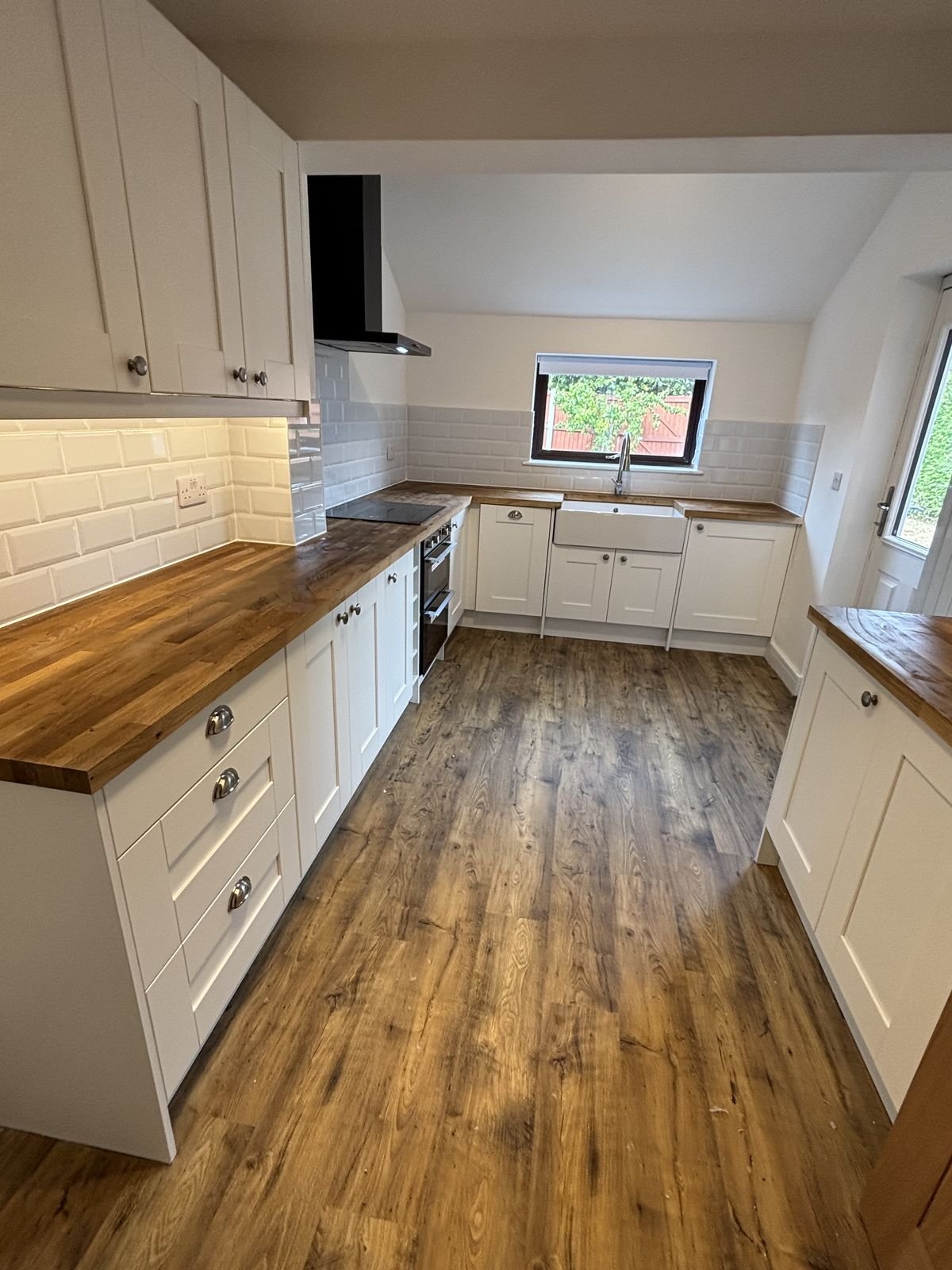 A cream shaker kitchen with timber worktops and a Belfast sink