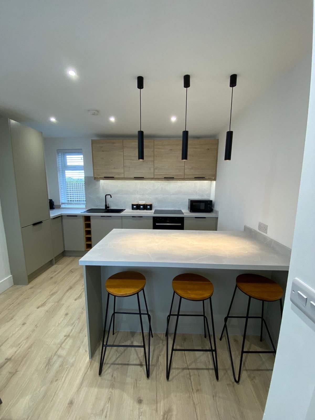 An oak and sage kitchen with a peninsula