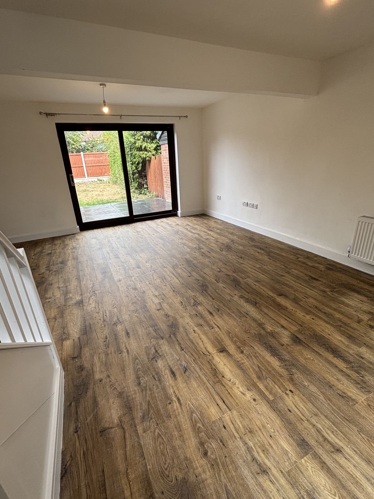 A living room with new flooring and sliding doors