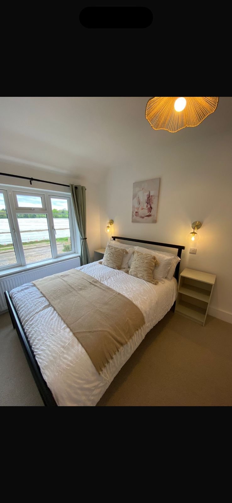A bright double bedroom with a rattan pendant