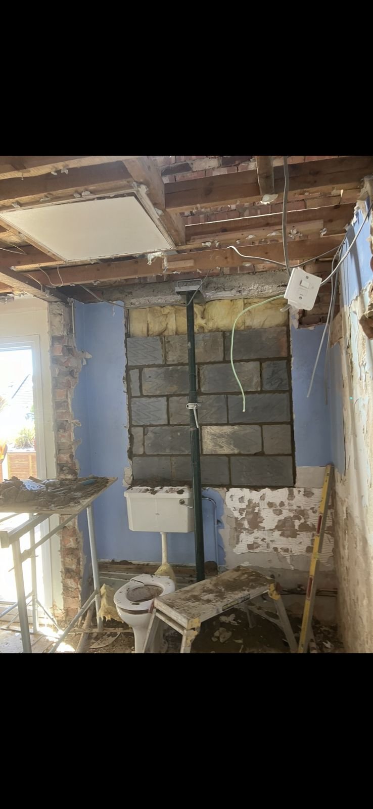 A room stripped back to brick with a prop holding the ceiling