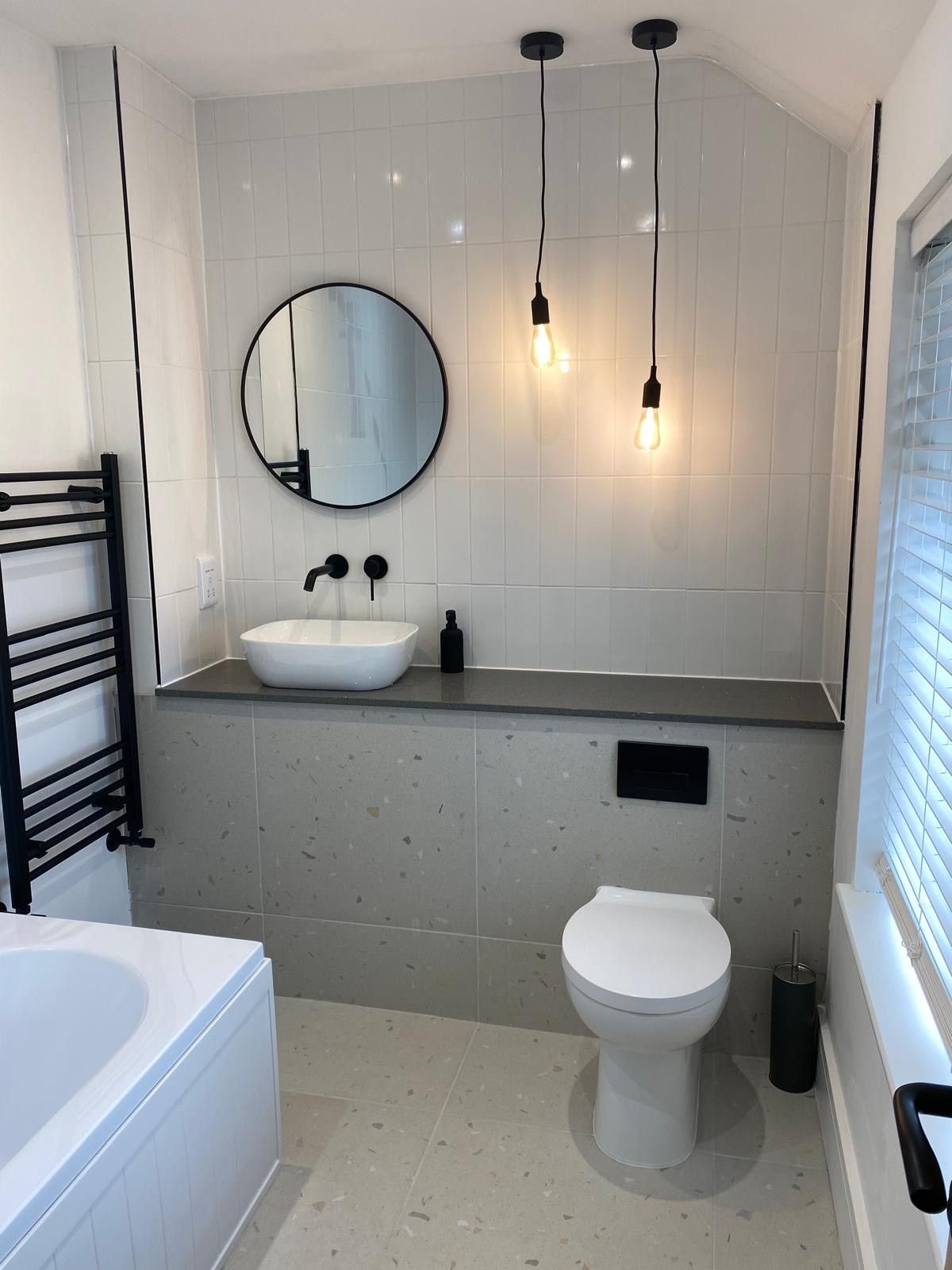 A bathroom with terrazzo tiling and pendant bulbs